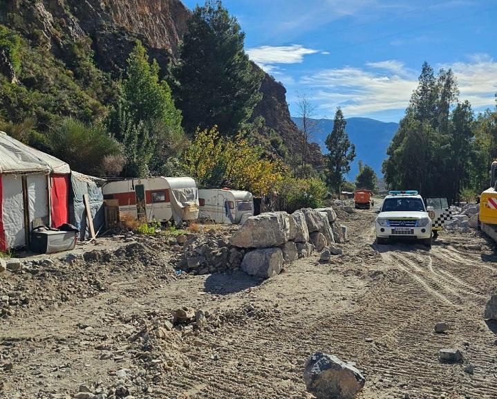 Zona de aparcamiento y asentamiento en rambla del cauce, donde se está instalando una escollera con grandes piedras.