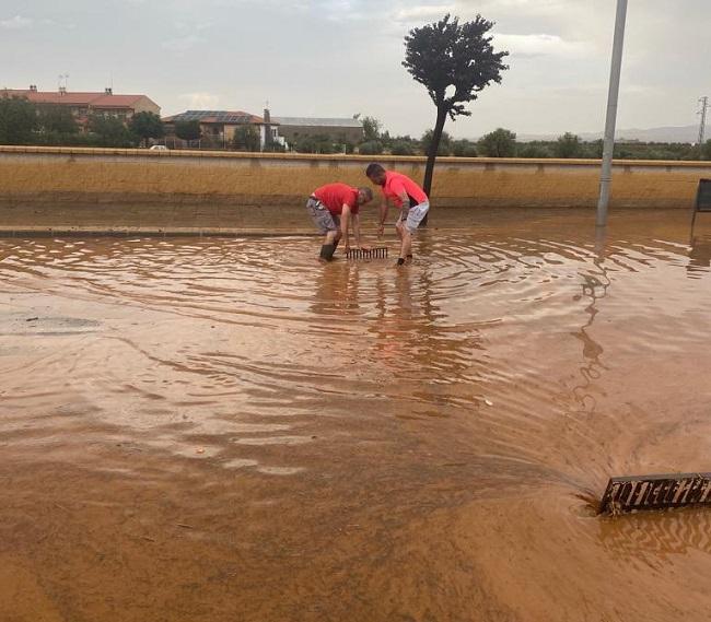 Operarios abren alcantarillas en una zona anegada. 