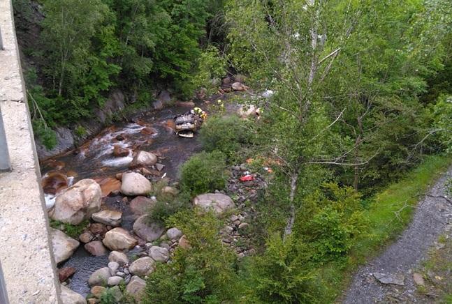 Equipos de salvamento, junto al coche, volcado, en el cauce del río. 