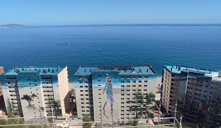 Vista del mural pintado sobre edificios de 12 plantas frente a la playa de Velilla. 