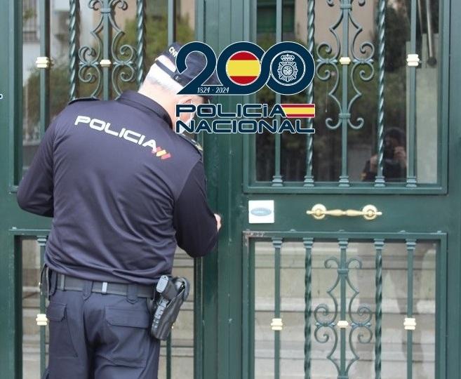 Un agente examina la puerta de entrada a un inmueble. 