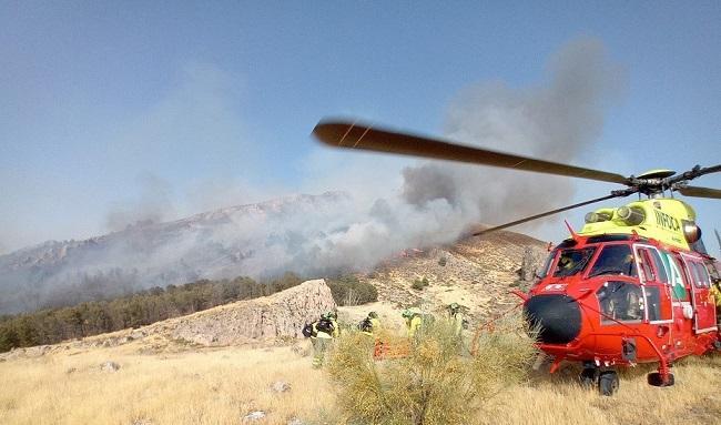 Un helicóptero y bomberos del Infoca en la zona del incendio de Pinos Puente.