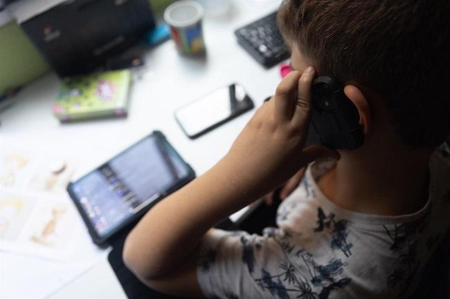 Un niño usa el teléfono móvil y una tablet