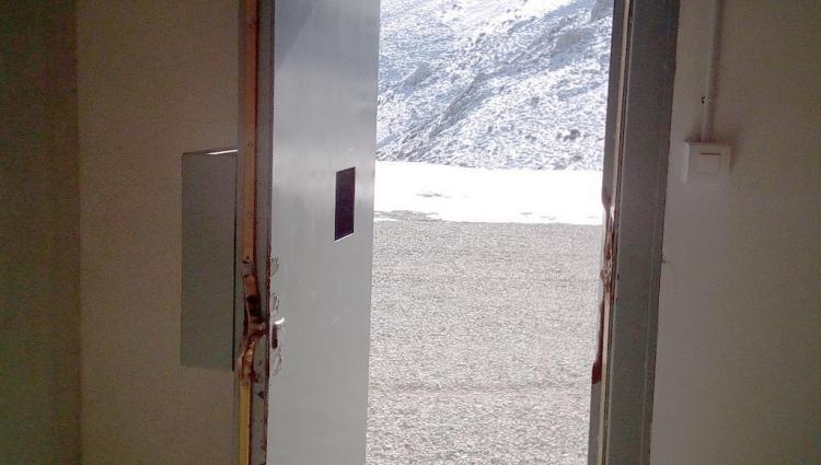 Puerta de entrada al edificio de acceso a la Cueva del Agua, reventada.