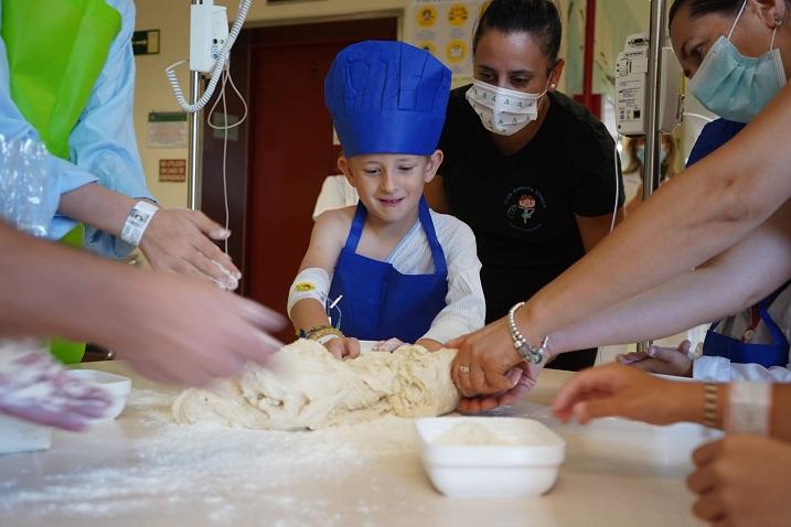 Un pequeño junto a su madre amasando pan en el hospital. 