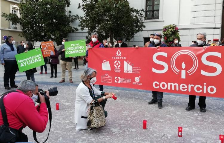 Una comerciante enciende una vela durante la concentración para lanzar un SOS por el sector.