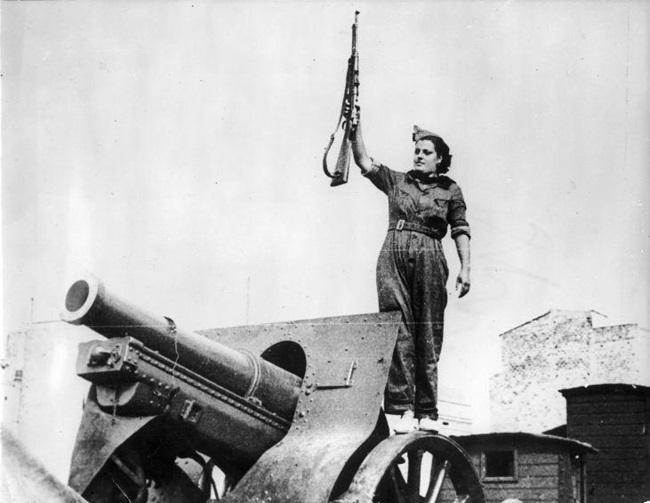 Miliciana posa con un rifle sobre un cañón en Barcelona (1936).