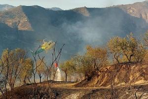 Un helicóptero descarga agua sobre el incendio de Pinos Genil. 