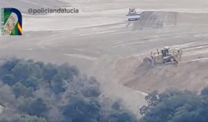 Una de las máquinas vierte tierra sobre el barranco y su vegetación. 